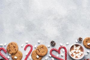 The chocolate chip cookie, Christmas cane caramel Cup cocoa and marshmallow cones Decorations on a gray background. Copy space Frame. photo