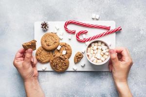 The chocolate chip cookie, Christmas cane caramel Cup cocoa and marshmallow cones Decorations on a gray background. Copy space Frame. photo