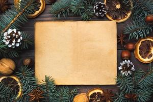 Frame of Christmas tree cones oranges nuts on dark wooden background. Copy space. Flat lay. Old paper for text. photo