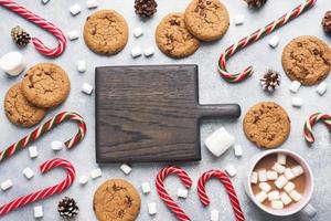 The chocolate chip cookie, Christmas cane caramel Cup cocoa and marshmallow cones Decorations on a gray background. Copy space Frame.