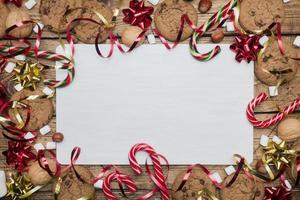 galletas con trocitos de chocolate bastones de navidad caramelo oro rojo paisaje y malvavisco sobre fondo de madera. copie el marco del espacio. foto