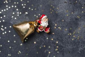 el concepto de noche de navidad. santa arrastra una bolsa de regalos fondo de estrella oscura. copie el espacio foto