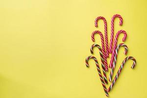 Christmas caramel canes on a yellow background. Holiday festive celebration greeting card with copy space to adding text. photo