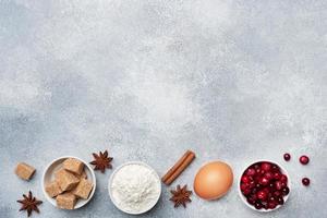 Ingredients for baking cookies, cupcakes and cake. Raw foods eggs flour sugar cranberries on a grey background with copy space. photo