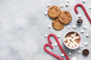 The chocolate chip cookie, Christmas cane caramel Cup cocoa and marshmallow cones Decorations on a gray background. Copy space Frame. photo
