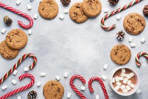 The chocolate chip cookie, Christmas cane caramel Cup cocoa and marshmallow cones Decorations on a gray background. Copy space Frame. photo
