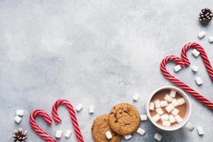 The chocolate chip cookie, Christmas cane caramel Cup cocoa and marshmallow cones Decorations on a gray background. Copy space Frame. photo