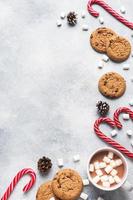The chocolate chip cookie, Christmas cane caramel Cup cocoa and marshmallow cones Decorations on a gray background. Copy space Frame. photo