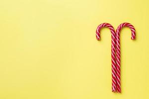 bastones de caramelo de Navidad sobre un fondo amarillo. tarjeta de felicitación de celebración festiva con espacio de copia para agregar texto. foto