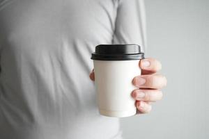 mano sosteniendo una taza de papel de café caliente. foto