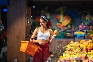 young woman do shopping in supermarket. choosing apples in store photo