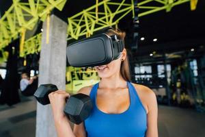 Woman wearing glasses of the virtual reality exercising with dumbbells photo