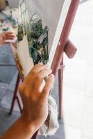 primer plano de la mano de la mujer aplicando pintura a un lienzo foto