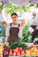 joven vendedora sosteniendo tomates de cosecha propia en las manos foto