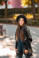 mujer elegante en poncho y sombrero disfruta del parque de otoño foto