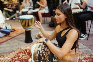 A young beautiful woman plays a hand drum photo