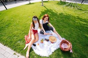 Two women having picnic together, sitting on the plaid photo