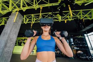 Woman wearing glasses of the virtual reality exercising with dumbbells photo