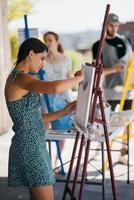 Young woman artist paints with a spatula on the canvas photo