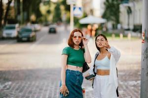 Two tourist friends consulting an online guide on a smart phone in the street photo