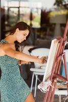 Young woman artist paints with a spatula on the canvas photo