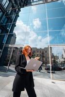 Smiling female looking at her laptop outdoors, modern lifestyle. photo