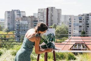 Young artist paints against the background of the city photo