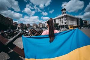 Young woman carries the flag of Ukraine fluttering behind her photo