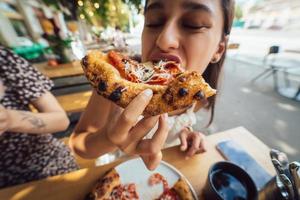 encantadora joven hermosa mujer está comiendo pizza. foto