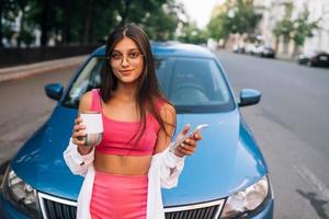 mujer conducir coche detener pausa para tomar café, usar teléfono inteligente foto