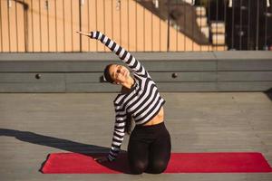 Woman doing yoga exercises on house roof in early morning photo