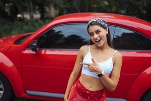 retrato de una mujer bastante caucásica parada contra un auto rojo nuevo foto