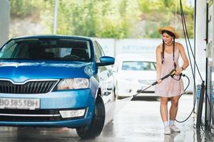 Brunette from a high-pressure hose washes the car photo