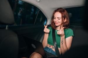 Beautiful woman is using laptop while sitting on back seat photo