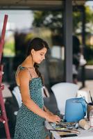 Young woman artist stands close table with a palette photo