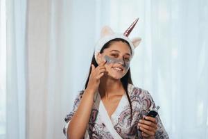 Woman applying facial mask on her face. Skin care concept photo