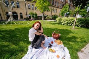 Happy young woman sitting on a blanket at the park lawn photo