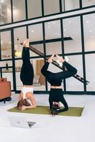 Two young woman working out indoors, doing yoga exercise on mat photo