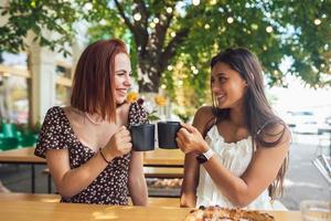 Two friends drinking coffee - women clinking with cups of coffee photo