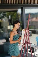 Young woman artist paints with a spatula on the canvas photo