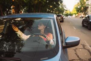 hermosa morena arreglando el espejo retrovisor del coche. foto
