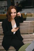 Young woman uses the phone at the street cafe photo