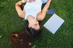 Young fit attractive woman lying on green lawn park. photo