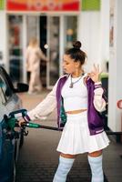 mujer llenando su auto con combustible en una gasolinera foto