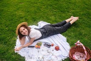 mujer joven feliz acostada sobre una manta en el césped del parque foto