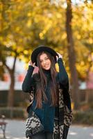 Stylish woman in poncho and hat enjoys autumn's park photo