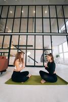 Two young women meditating in lotus pose with hands in namaste. photo