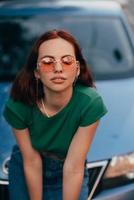 Beautiful girl sits on the hood of a blue car photo