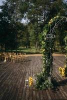 Wedding arch is decorated with green leaves and lemons. photo