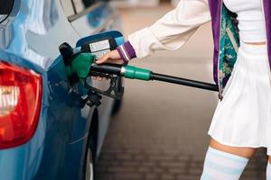 mujer llenando su auto con combustible en una gasolinera foto